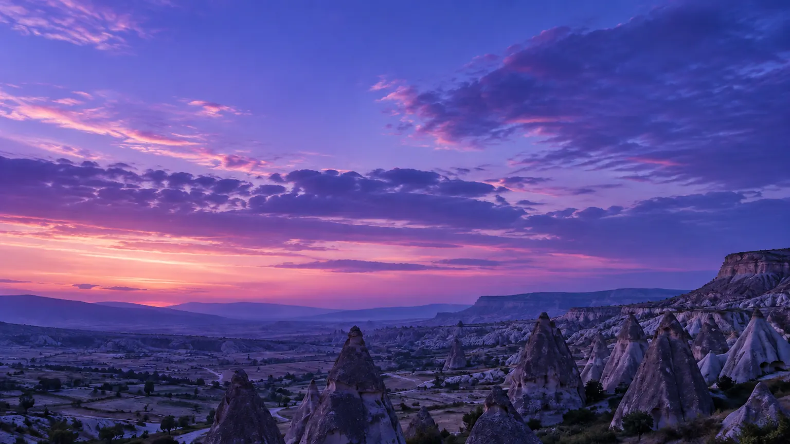 Valle de chimeneas de roca bajo un cielo violeta al atardecer (imagen generada con AI)